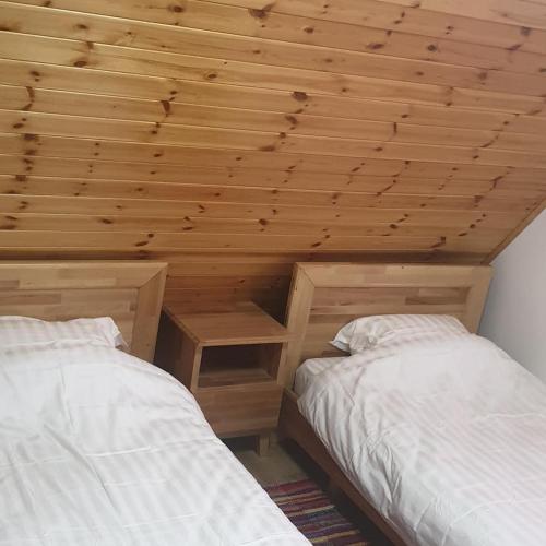 two beds in a room with a wooden ceiling at Bujtinat e lugines Valbone in Valbonë