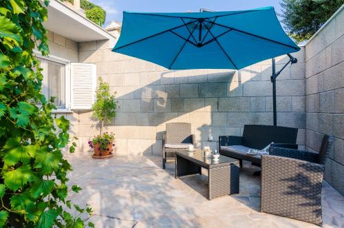 eine Terrasse mit einem blauen Sonnenschirm, Stühlen und einem Tisch in der Unterkunft Apartments L&M in Dubrovnik