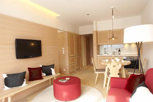 a living room with a red couch and a red stool at Falkensteiner Residences edelweiss in Katschberghöhe