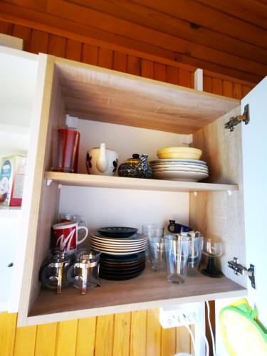 a cupboard with plates and dishes in it at MERIKOTKA - a cozy wooden cottage, sLOVEnia in Braslovče