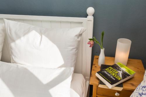 a bed with a book and a vase on a table at Gutshaus Lexow in Lexow