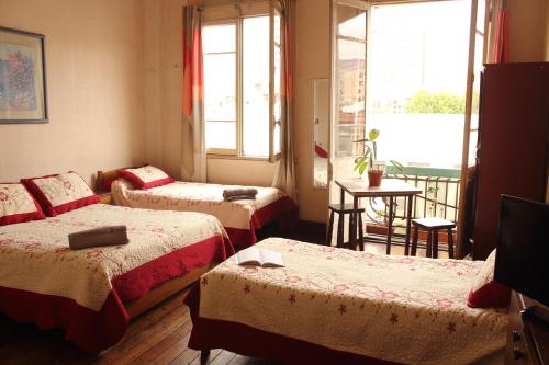 a hotel room with three beds and a balcony at Hostal Fiorenttina in Valparaíso