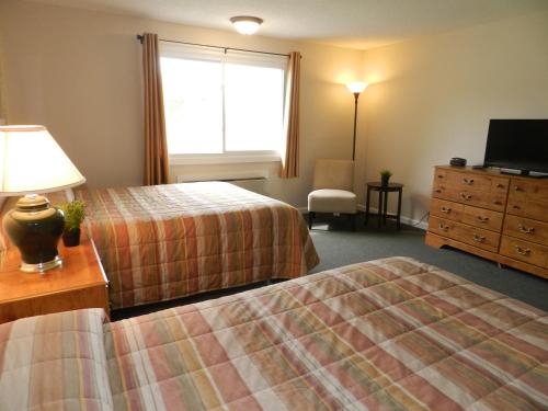 a hotel room with two beds and a dresser and a window at C-Way Resort in Clayton