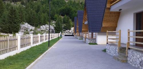 a sidewalk next to a fence next to a building at Bujtinat e lugines Valbone in Valbonë