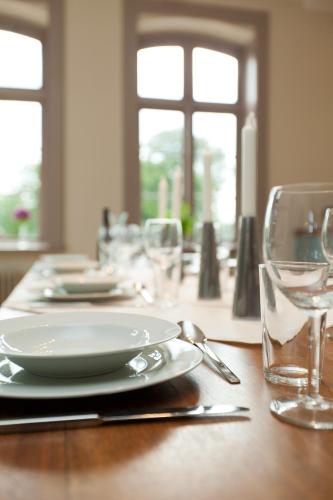 a wooden table with a plate and glasses on it at Gutshaus Lexow in Lexow