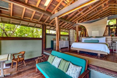 a bedroom on a porch with a bed and a couch at Morgan's Rock in San Juan del Sur