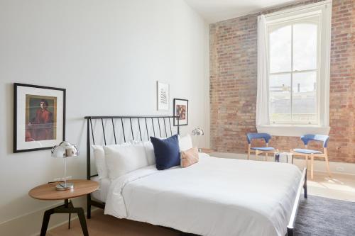 a bedroom with a white bed and a brick wall at Sonder Gravier Place in New Orleans