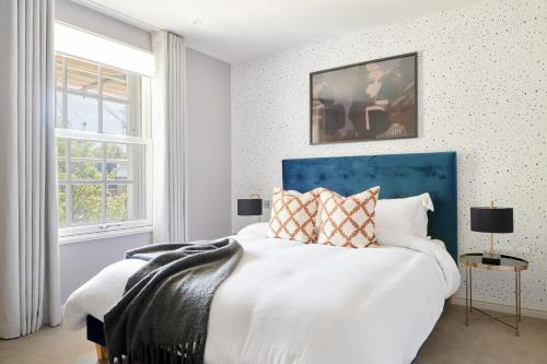 une chambre avec un grand lit et une tête de lit bleue dans l'établissement Sonder Sloane Square, à Londres