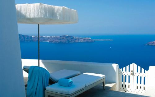 a blue room with a white couch and a view of the ocean at White Santorini in Imerovigli