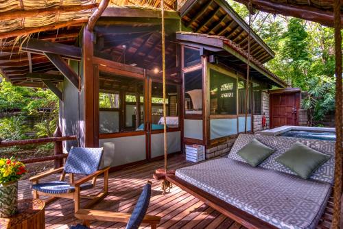 a house with a porch with a bed and a swing at Morgan's Rock in San Juan del Sur