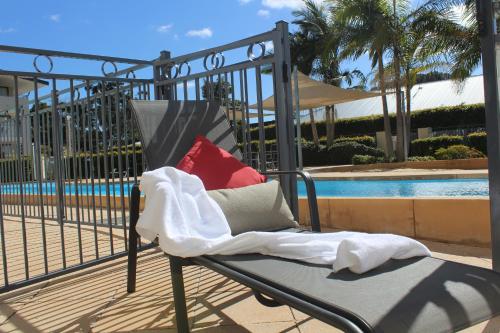 a chair with pillows sitting next to a pool at The Boathouse Resort Luxury Apartments in Tea Gardens
