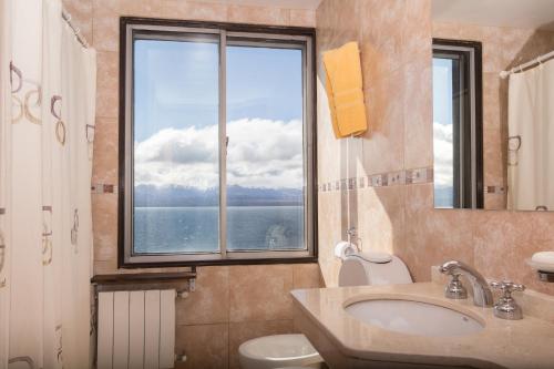 uma casa de banho com um lavatório, um WC e uma janela. em Hospedaje Penthouse 1004 em San Carlos de Bariloche