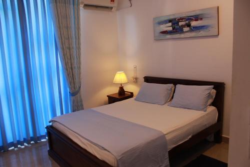 a bedroom with a bed with blue curtains and a lamp at Dominic's best in Mount Lavinia