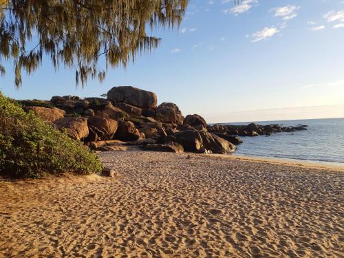 a sandy beach with rocks and the ocean at Whitsunday Sands Resort in Bowen