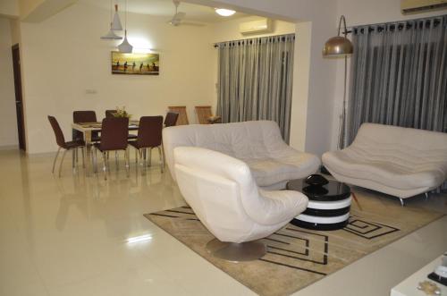 a living room with white chairs and a table at Atrium - ICONIC APARTMENT in Sri Jayewardenepura Kotte