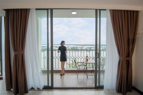 a woman standing on a balcony looking out the window at Cuu Long Hotel in My Tho