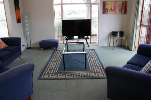 a living room with a flat screen tv and blue chairs at Quality Inn Acapulco Taupo in Taupo