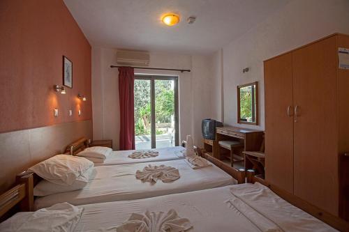 een slaapkamer met 2 bedden, een bureau en een raam bij Apostolis Hotel Apartments in Pefki Rhodes