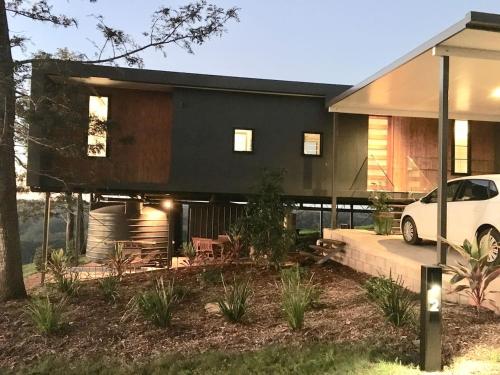 a black house with a white car parked in front of it at Scandinavian Cabin - Maleny - One Bedroom in Maleny