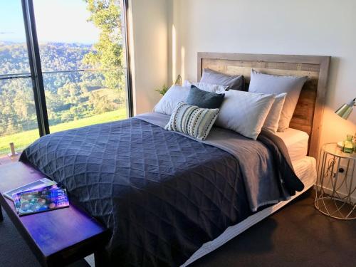 a bedroom with a large bed with a large window at Scandinavian Cabin - Maleny - One Bedroom in Maleny