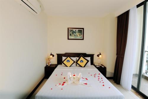 a bedroom with a bed with red rose petals on it at Cuu Long Hotel in My Tho