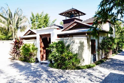 a white house with a gate and palm trees at The Villas of Byron in Byron Bay