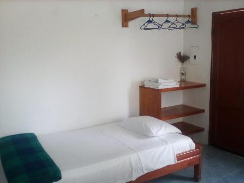 a bedroom with a white bed and a shelf at Hospedaje Sarita in Puerto Villamil
