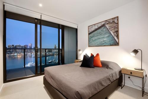 a bedroom with a bed and a large window at Orange Stay at Collins Wharf in Melbourne