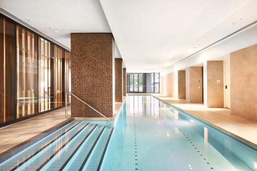 a swimming pool in a building with glass windows at Orange Stay at Collins Wharf in Melbourne
