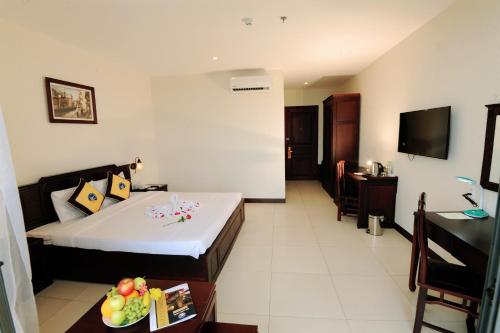 a hotel room with a bed and a table with a bowl of fruit at Cuu Long Hotel in My Tho
