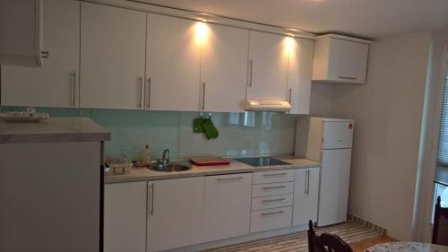 a kitchen with white cabinets and a sink and a refrigerator at Apartman centar lux in Tuzla