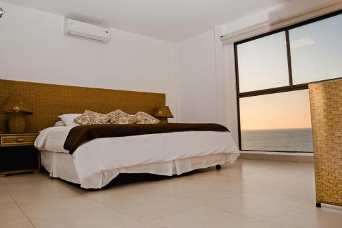 a bedroom with a large bed and a large window at Hotel Vistalmar in Manta