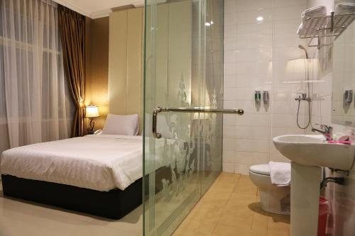 a bathroom with a shower and a bed and a sink at Hotel 55 in Jakarta