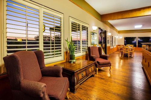 a living room with chairs and a table and windows at Super 8 by Wyndham Lindsay Olive Tree in Lindsay