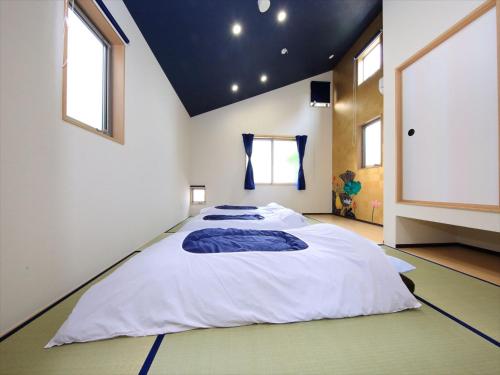 um quarto com uma grande cama branca num quarto com janelas em COTO Tokyo Nakano em Tóquio