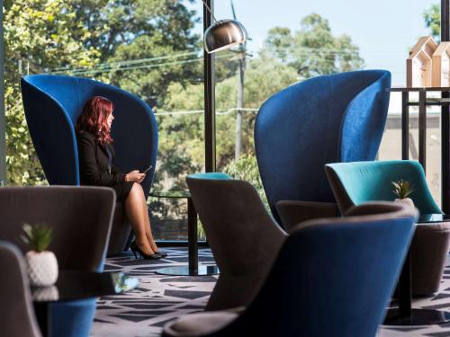 a woman sitting in a chair on a phone at Pullman Sydney Airport in Sydney