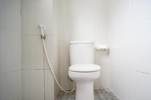 een wit toilet in een badkamer met een slang bij OYO 1477 Athar 88 Hotel in Balikpapan