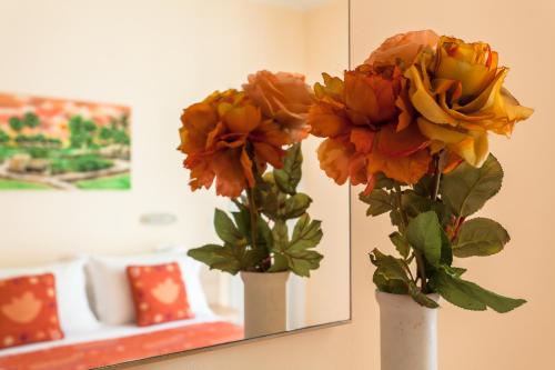 two vases with flowers in front of a mirror at Hotel Giove dipendenza Hotel Fiamma in Cesenatico