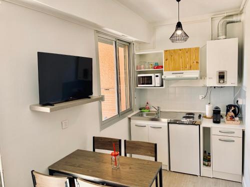 Il comprend une cuisine avec une table et une télévision murale. dans l'établissement Très beau studio à 100m de la plage de Marinella, à Ajaccio