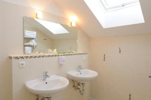 a bathroom with two sinks and a mirror at Hotel Inspiration Garni in Tittmoning