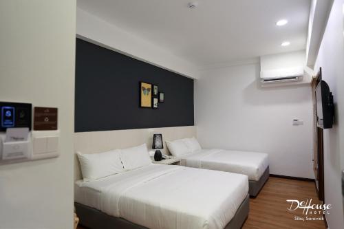a hotel room with two beds and a tv at De House Hotel in Sibu