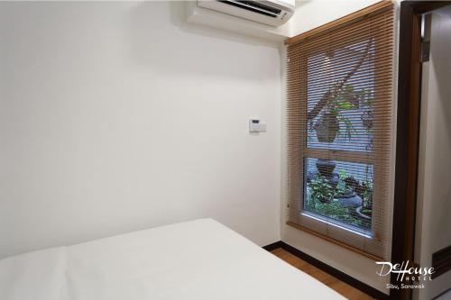 a bedroom with a bed and a window with blinds at De House Hotel in Sibu