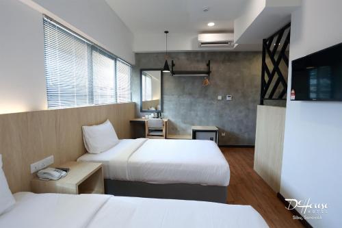 a hotel room with two beds and a table at De House Hotel in Sibu