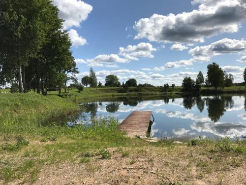 a small lake with a wooden dock in a field at SKY Ranch in Izborsk