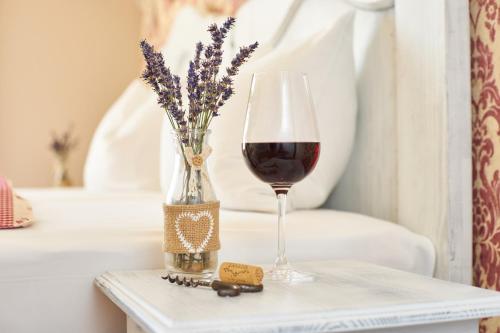 a glass of wine and a vase of flowers on a table at Takler Kúria in Szekszárd