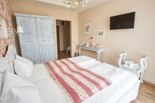 a bedroom with a white bed with a tv on the wall at Takler Kúria in Szekszárd