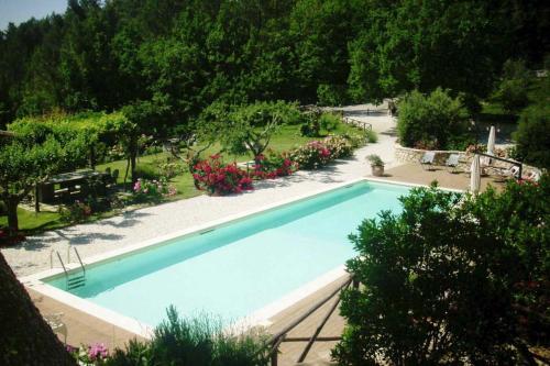a large swimming pool in a garden with flowers at Torre del Falco in Spoleto