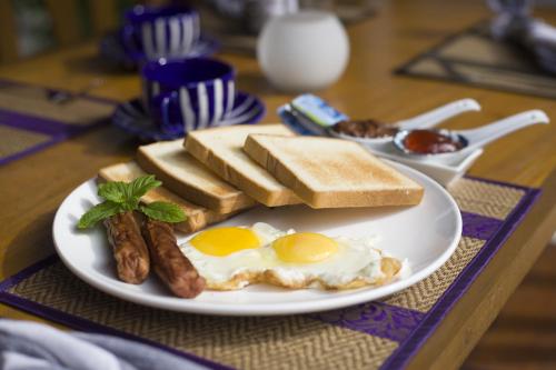 a plate with eggs sausage and toast on a table at By the shade Maldives in Hangnaameedhoo