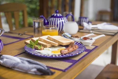 a table with a breakfast plate of eggs sausage and toast at By the shade Maldives in Hangnaameedhoo