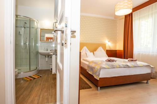 um quarto com uma cama e uma casa de banho com um chuveiro em Hotel Pávai em Hajdúszoboszló